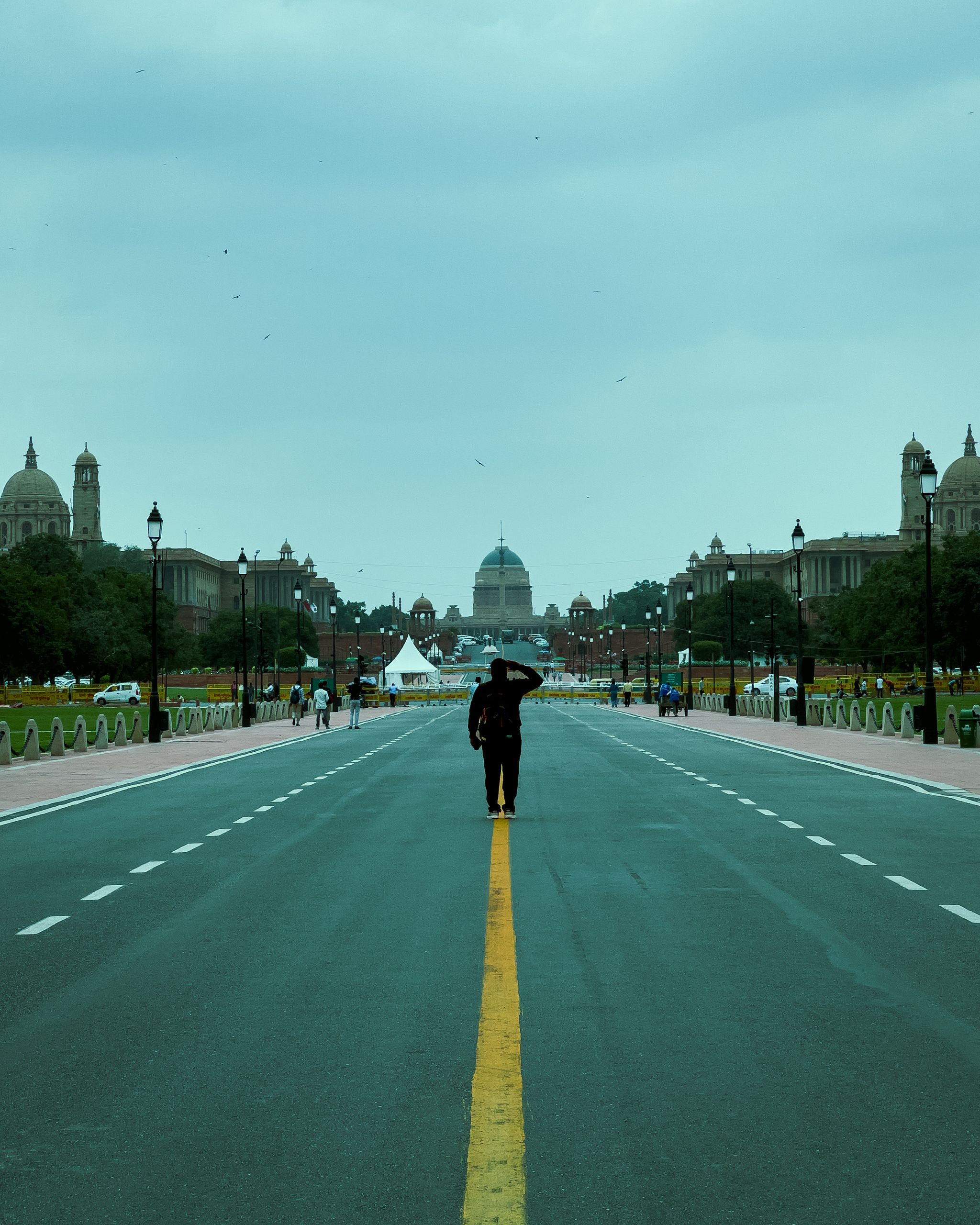 A lone soldier salutes on the iconic Rajpath with Rashtrapati Bhavan in the background.