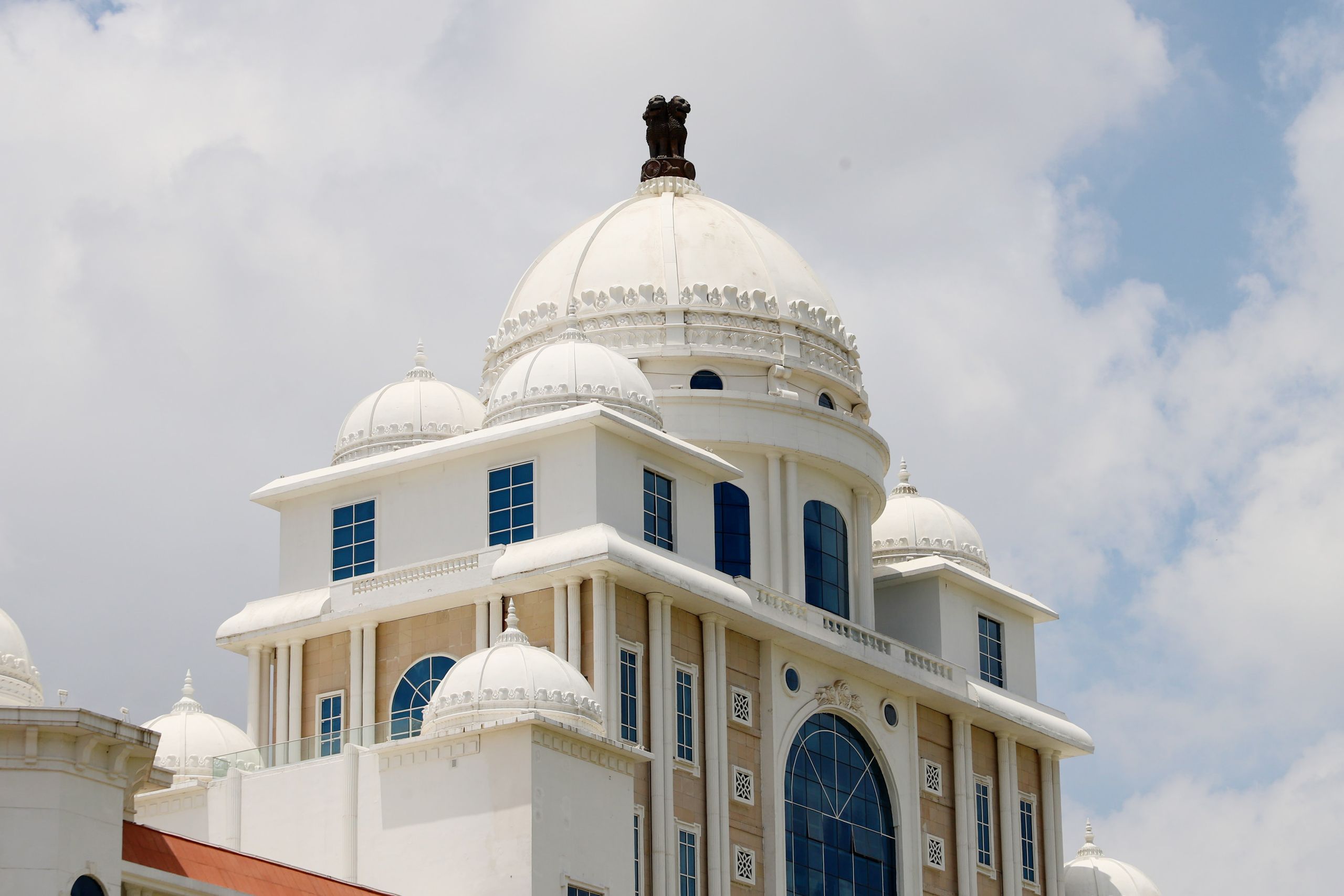 Elegant white dome building with architectural beauty under a bright blue sky and scattered clouds.